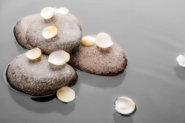 Piedras y pétalos de flores en agua. Estilo de vida zen
 - Foto, Imagen