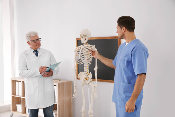 Medical student and professor studying human skeleton anatomy in classroom - Photo, Image