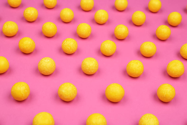 Many delicious lemon drops on pink background - Foto, afbeelding