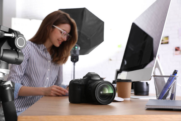 Professional photographer working at table in office, focus on camera - Foto, Imagem