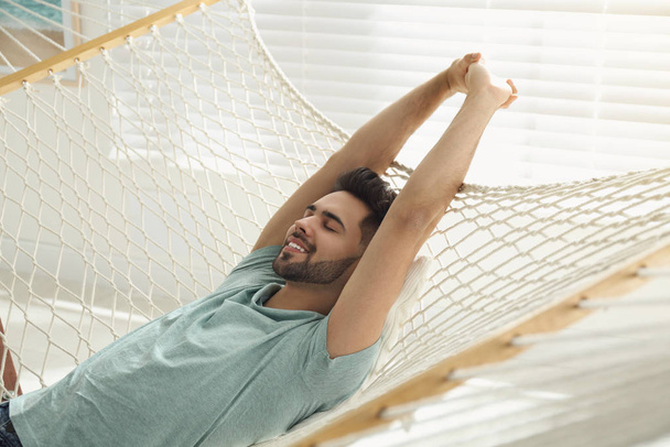 Young man relaxing in hammock at home - Fotó, kép