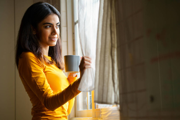 Donna persiana che beve caffè guardando attraverso la finestra
 - Foto, immagini