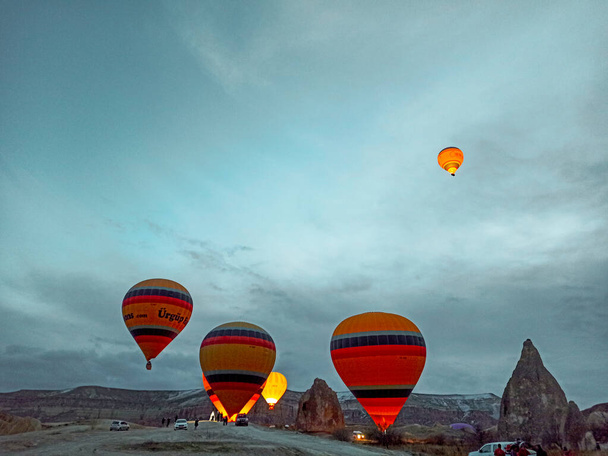 Colorful Hot Air Balloons flying over Cappadocia early morning at winter with dark morning in Turkey - Foto, afbeelding