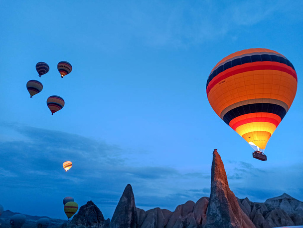 Colorful Hot Air Balloons flying over Cappadocia early morning at winter with dark morning in Turkey - Foto, afbeelding