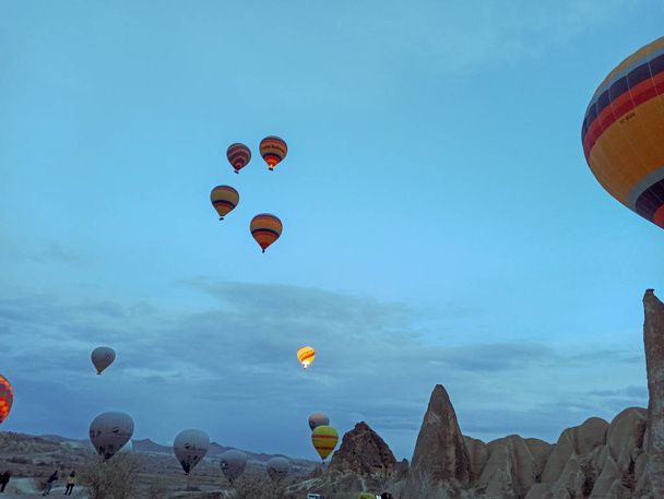 Colorful Hot Air Balloons flying over Cappadocia early morning at winter with dark morning in Turkey - Foto, Imagen