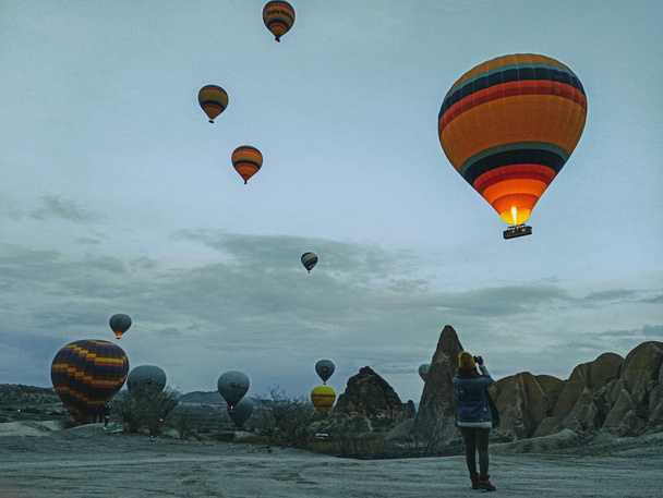 Kolorowe balony na gorące powietrze przelatujące nad Kapadocją wczesnym rankiem zimą z ciemnym porankiem w Turcji - Zdjęcie, obraz
