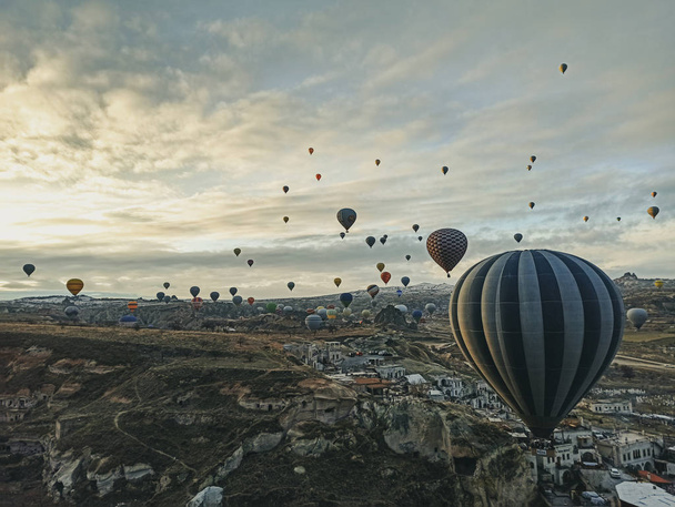 Colorful hot air balloons flying at the sunrise with rocky landscape in Cappadocia, Turkey - Foto, imagen