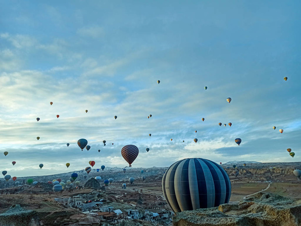 Colorful hot air balloons flying at the sunrise with rocky landscape in Cappadocia, Turkey - Fotó, kép