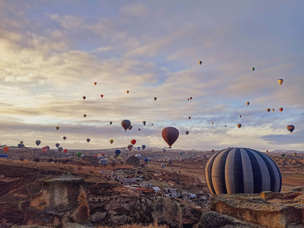 Színes hőlégballonok repülnek a napfelkeltekor sziklás tájjal Cappadociában, Törökországban - Fotó, kép