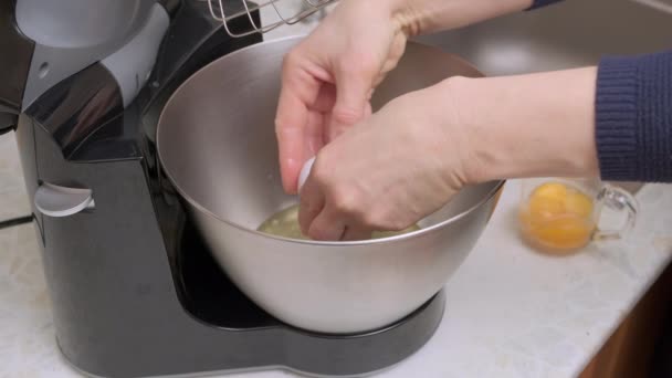 as mãos da mulher quebram o ovo e dividem a proteína e a gema na tigela de metal do processador de alimentos. Vista de perto
 - Filmagem, Vídeo