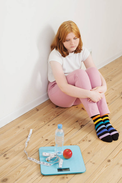 sad teenager girl with scale on wooden floor - Photo, image
