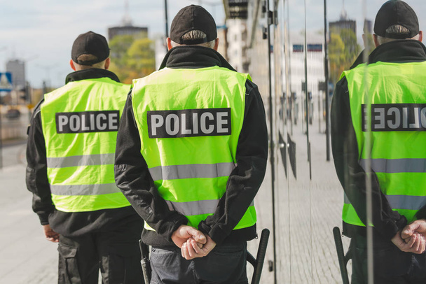 Word police written on reflective vests of police officers - Fotoğraf, Görsel