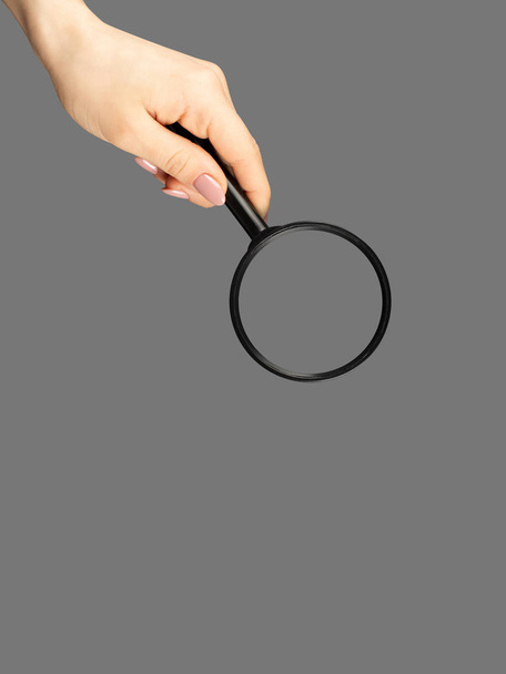 Hand holding magnifying glass on gray background - Photo, Image