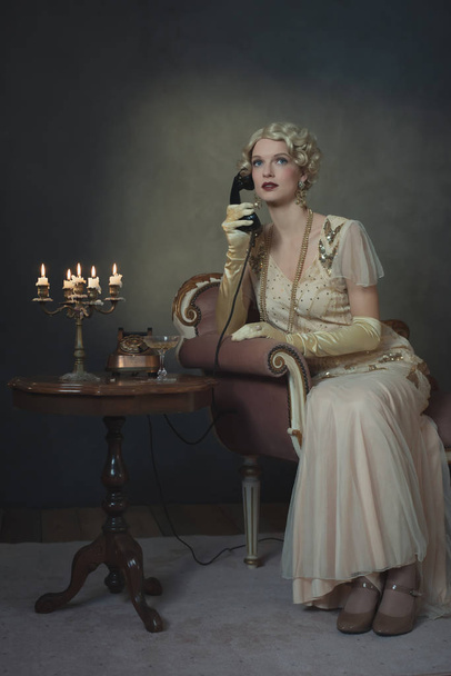 Retro-Mode der 1920er Jahre am Telefon, während man auf dem Sofa sitzt - Foto, Bild