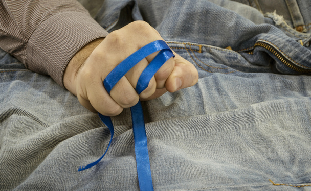 the blue ribbon is clenched in a fist.  - Фото, изображение