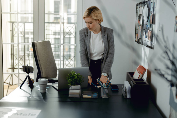 Pretty woman standing near desktop in the office - Fotó, kép