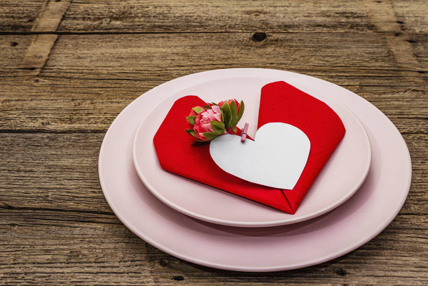 Romantický jídelní stůl s talíři a ubrouskem ve tvaru srdce. Milostný koncept na Valentýna nebo na Den matek, svatební příbory. Ročník dřevěné desky pozadí - Fotografie, Obrázek