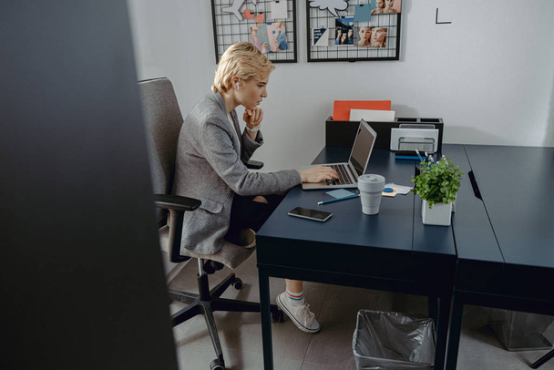 Young woman is using wireless headphones in the office - Fotó, kép