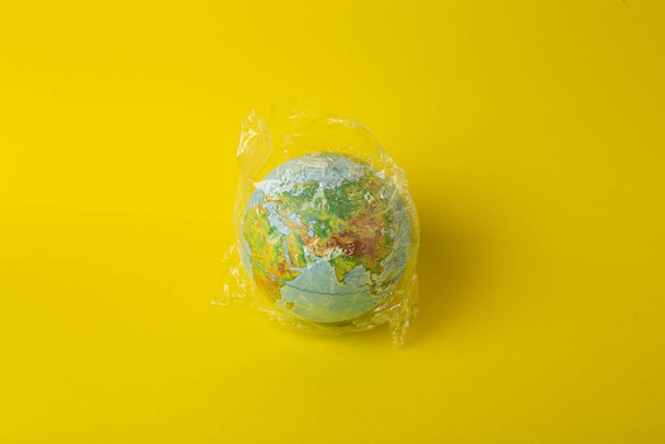 Plastic bag pollution concept. Earth globe in a plastic bag on a - Φωτογραφία, εικόνα