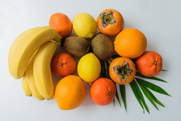 Bananen, persimmons, sinaasappel, mandarijn, kiwi op een witte achtergrond. - Foto, afbeelding