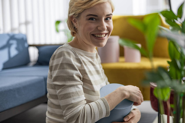 Happy pretty lady sitting in living room and smiling - Foto, imagen