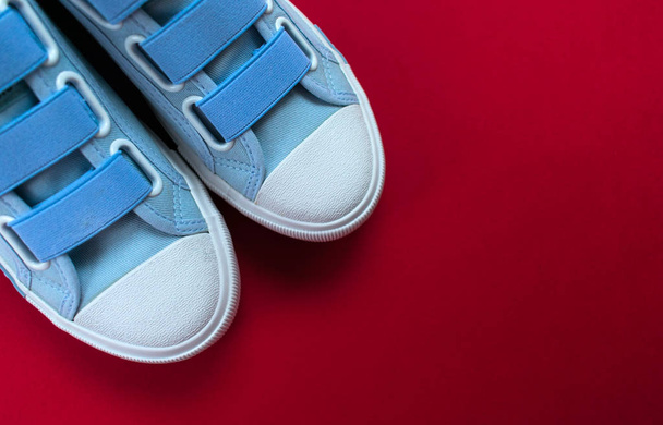 Новая пара синих кроссовок на красном фоне с копировальным пространством. Стиль жизни, спортивная обувь
. - Фото, изображение