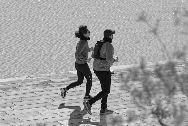 Italy, Sicily, Marina di Ragusa (Ragusa Province); 18 January 2020, couple running in the port - EDITORIAL - Фото, изображение