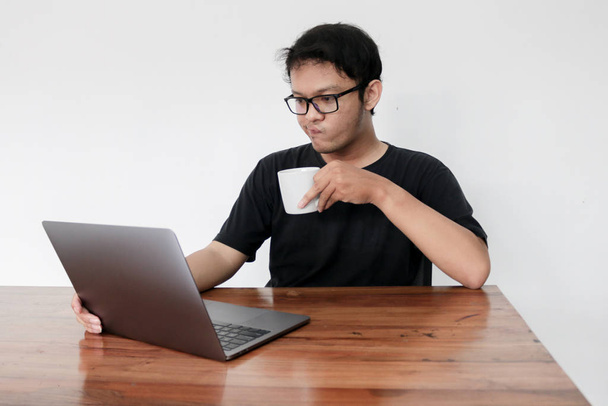young asian man working and drinking coffee in studio - Foto, afbeelding