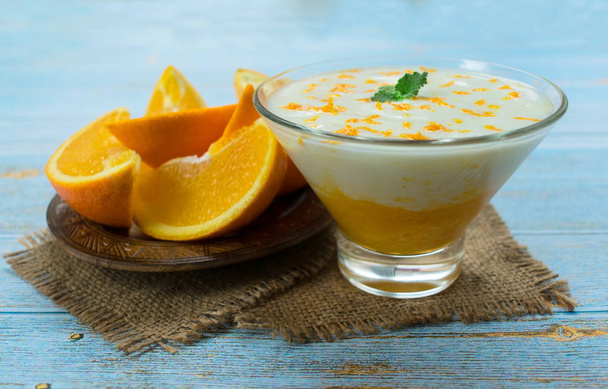  Здоровий йогурт з апельсиновою смугою на синьому дерев'яному фоні. Концепція здорових десертів
. - Фото, зображення