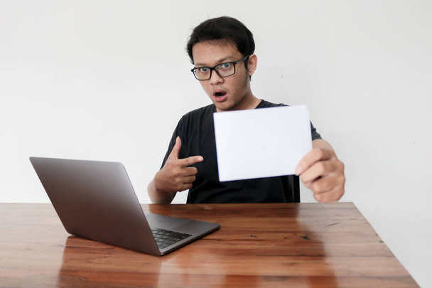 Азиатский мужчина с белым листом бумаги работает в студии
 - Фото, изображение