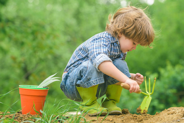 Agricultura ecológica. El niño trabaja con el suelo. El juego del granjero. El chico en el jardín
. - Foto, imagen