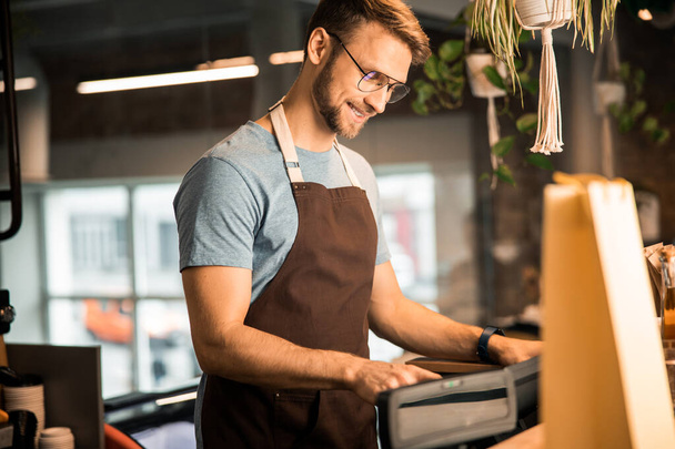 Щасливий молодий чоловік працює в кав'ярні
 - Фото, зображення