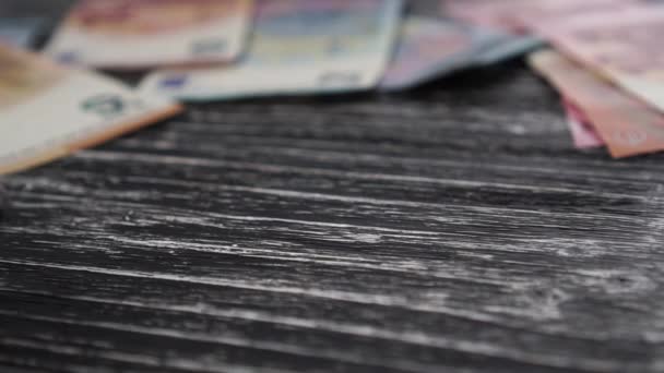 黒いサイコロロールとユーロ紙幣と黒の質感の木製の古いテーブルの上にロールオーバー.上の数字2で停止します。金のためのギャンブル。スローモーション - 映像、動画