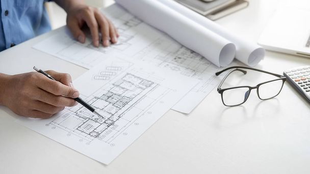 Architect or Engineer working in office with engineering tools, blueprint and building model. Construction concept. - Photo, image