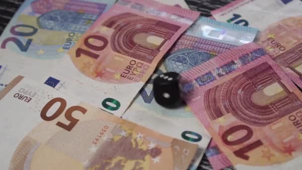 Black dice rolls and rolls over on a table with euro banknotes. Stops with the number 3 on top. Gambling for money. Slow motion - Materiał filmowy, wideo