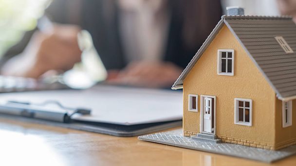 Модель будинку з агентом і клієнтом обговорюють контракт, щоб купити, отримати страхування або кредит нерухомості або майна. - Фото, зображення