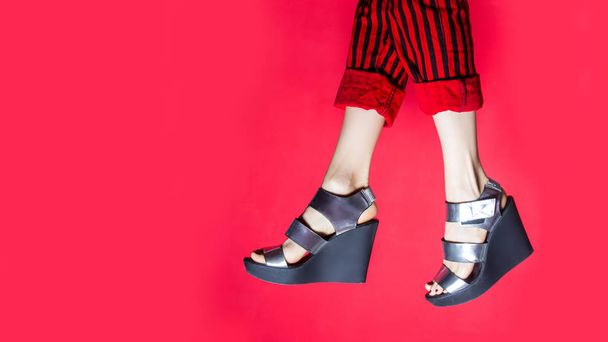 Jambes féminines portant des chaussures d'été sur fond rouge vif
 - Photo, image