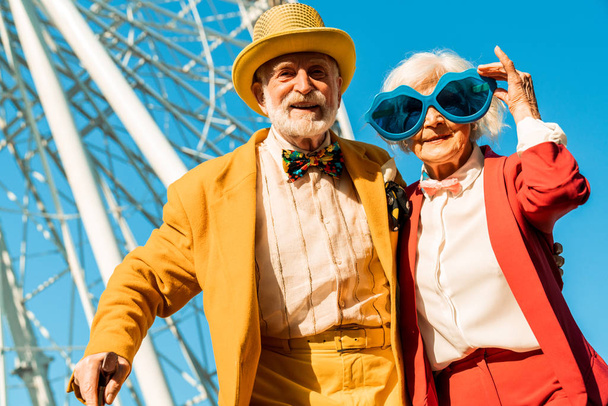 Happy cheerful elderly couple posing in colorful costumes - Фото, зображення