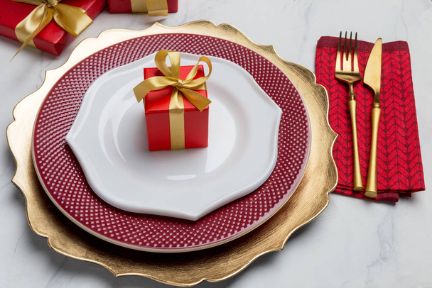 Gift box on empty plate with table setting and golden tableware - Foto, immagini