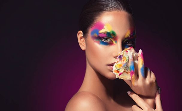Beautiful girl with festive bright multi-colored make up on the face. Young woman dressed in extravagant art makeup .Twinkling stars on a black background. Holiday ,celebration, cosmetic and beauty . - Photo, Image