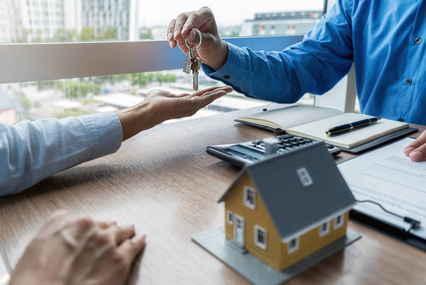 Agent immobilier détenant une clé et demandant au client un contrat pour acheter, obtenir une assurance ou un prêt immobilier ou immobilier. - Photo, image