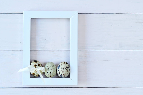White photo frame and quail eggs on light background. Easter Postcard Template - Photo, Image