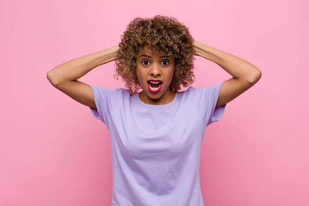 young african american woman feeling stressed, worried, anxious or scared, with hands on head, panicking at mistake against pink wall - Foto, Imagem
