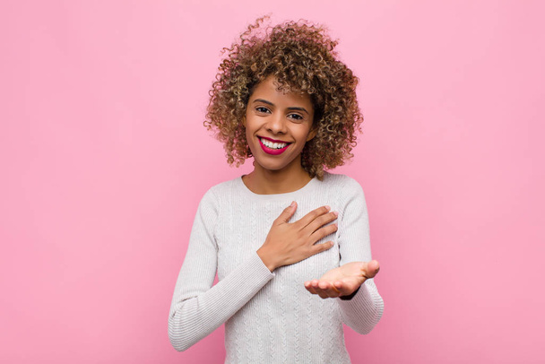 アフリカ系アメリカ人の若い女性が幸せと愛を感じながら手を心の隣に笑顔で - 写真・画像