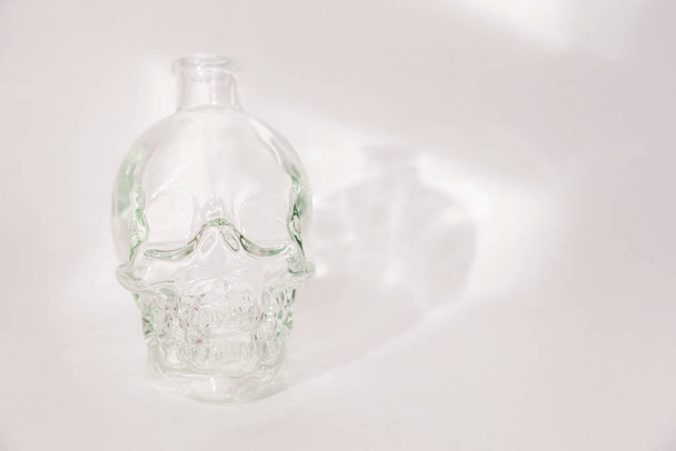 Jarra de vidrio en forma de cráneo humano sobre fondo blanco
 - Foto, Imagen