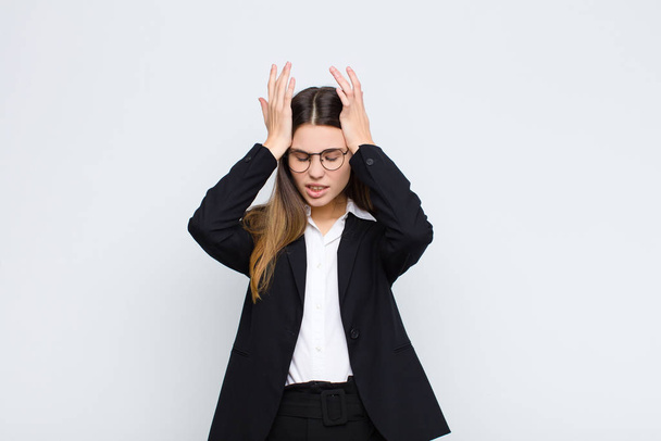 young businesswoman feeling stressed and anxious, depressed and frustrated with a headache, raising both hands to head against white wall - Fotografie, Obrázek