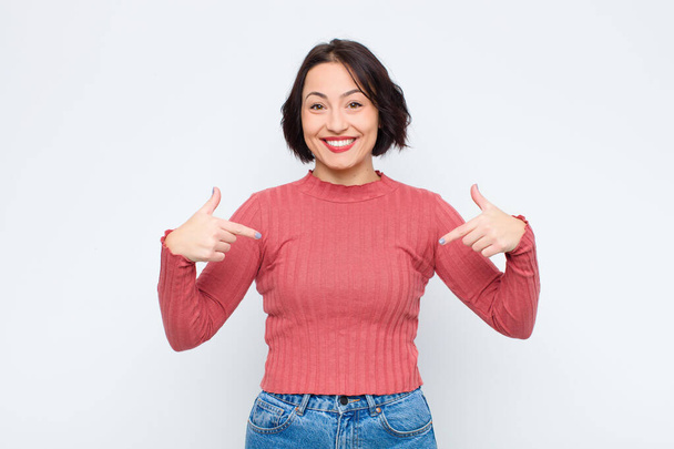 young pretty woman looking proud, positive and casual pointing to chest with both hands against white wall - 写真・画像