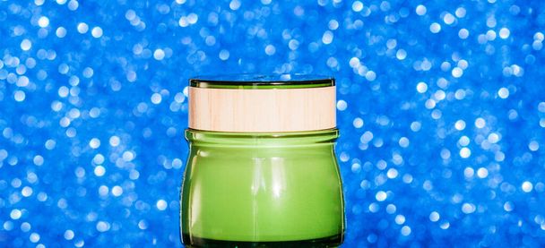 Green jar with face cream on a blue background - Fotoğraf, Görsel