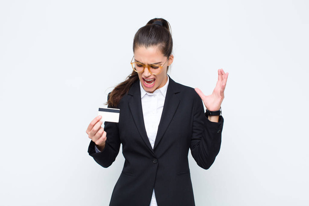young businesswoman screaming with hands up in the air, feeling furious, frustrated, stressed and upset with banknotes with bills - Fotoğraf, Görsel