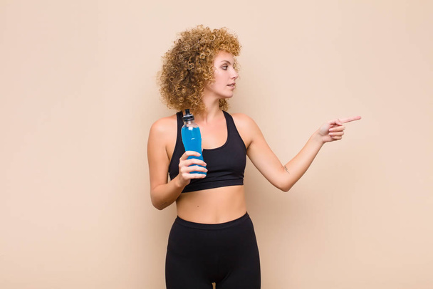 young afro woman standing and pointing to object on copy space, rear view sport concept - Photo, Image